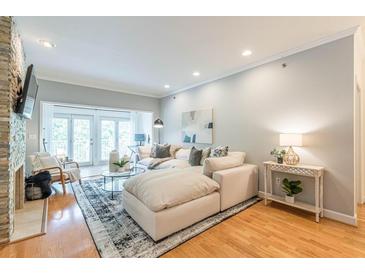 Bright living room with large sectional sofa, stone fireplace, and access to outdoor balcony at 2865 Lenox Road Ne # 602, Atlanta, GA 30324