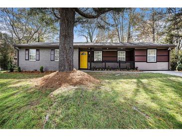 Charming exterior of home featuring a yellow front door, gray brick, and a well-manicured lawn at 2760 Swansea Ct, College Park, GA 30349