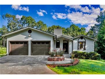 Charming home featuring an attached two car garage, landscaped front yard and stucco finish at 1310 Dillon Rd, Austell, GA 30168