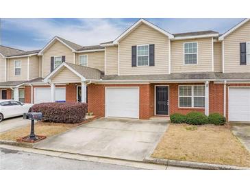 Charming townhome with brick and tan siding, showcasing an attached garage and well-maintained landscaping at 453 Tara Commons Cir, Loganville, GA 30052
