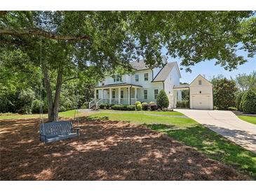 Stunning two-story white farmhouse with a swing on a tree and lush green lawn at 765 Hembree Rd, Alpharetta, GA 30076