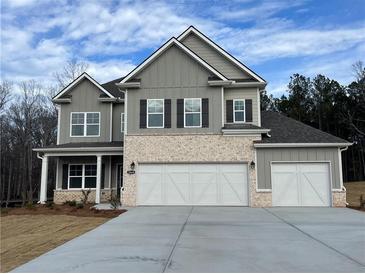 New two-story home featuring brick and gray siding, a three-car garage, and a well-manicured lawn at 897 Porches Way, Dacula, GA 30019