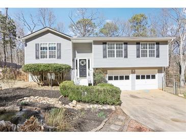 Split-level home featuring neutral siding, black shutters, and a well-maintained front yard with mature landscaping at 8740 Jenkins Rd, Winston, GA 30187