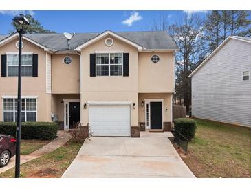 Two-story townhome features a one-car garage, well-kept lawn, and a neatly paved driveway at 2322 Coach Way, Jonesboro, GA 30236