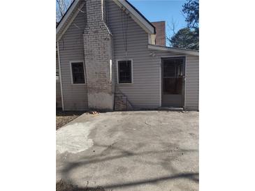 Exterior shot of the backyard with a gray facade and brick chimney, ready for outdoor enjoyment at 4031 Old Fairburn Rd, Atlanta, GA 30349