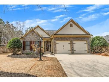 Charming home featuring stone accents, two-car garage, and manicured landscaping under a clear blue sky at 918 Bridge Mill Ave, Canton, GA 30114