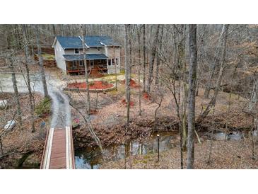 Charming home surrounded by mature trees and a quaint bridge leading to the property at 613 Rock Springs Pass, Dallas, GA 30157