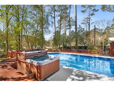 Inviting in-ground pool and hot tub surrounded by a wooden deck and lush trees, perfect for relaxation at 1175 Kingsley Ne Cir, Atlanta, GA 30324
