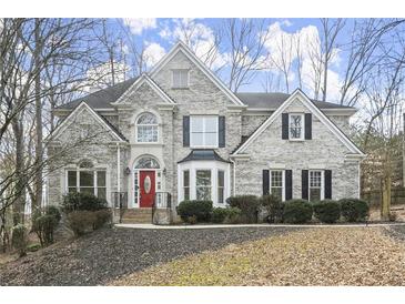 Beautiful two-story brick home with manicured landscaping and a red front door at 130 Cauley Club Ct, Johns Creek, GA 30097