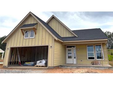 New construction with a yellow exterior, dark roof, and an attached garage, offering modern living at 33 Cambridge Ln, Dallas, GA 30157