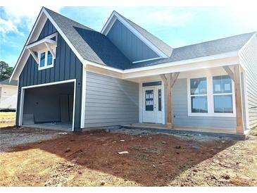 Charming home exterior with two-car garage, gray siding, and a covered front porch with wooden support beams at 33 Cambridge Ln, Dallas, GA 30157