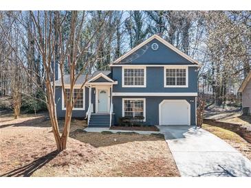 Charming two-story home with blue siding, white trim, an attached garage and well-maintained landscaping at 2111 Glenwood Downs Dr, Decatur, GA 30035