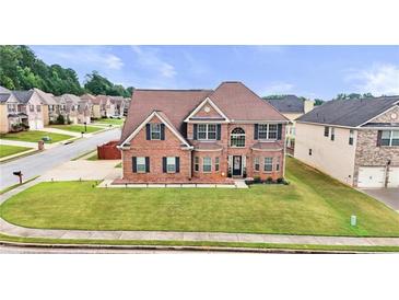 Inviting two-story brick home featuring a manicured lawn, arched entryway, and symmetrical window placement at 106 Dustin Dr, Stockbridge, GA 30281