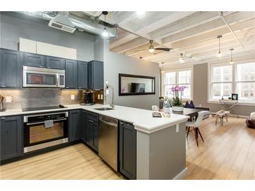 Modern kitchen featuring stainless steel appliances, dark cabinets, and a breakfast bar with seating at 32 Peachtree Nw St # 1105, Atlanta, GA 30303