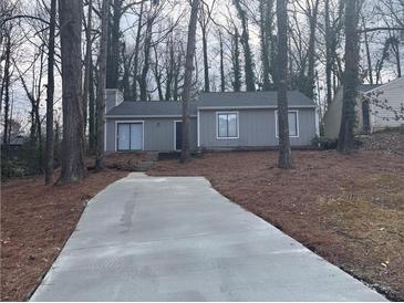 Charming single-story home with a gray exterior, surrounded by mature trees and featuring a long driveway at 5073 Martins Crossing Rd, Stone Mountain, GA 30088