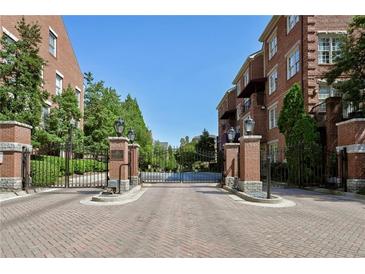 Brick buildings surround an ornate wrought iron gate with brick pillars on a paved road leading to a complex at 1735 Peachtree Ne St # 227, Atlanta, GA 30309