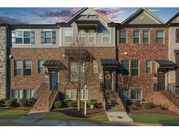 Charming townhome featuring a brick facade, individual entrances, and manicured landscaping at 4478 Dunblane Ave, Sugar Hill, GA 30518