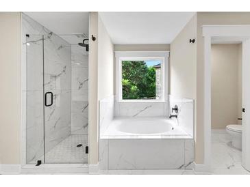 Elegant bathroom featuring a glass shower and a luxurious soaking tub with marble tile surround at 703 Sierra Ct, Canton, GA 30114
