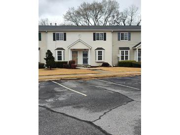 Townhouse with a beige exterior, black shutters, trimmed shrubbery, and front door metal security gate at 1625 Conley Rd # 171, Conley, GA 30288
