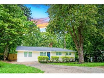 Charming single-story home with a well-manicured lawn, mature trees, and blue front door at 1975 Glenmar Dr, Decatur, GA 30032