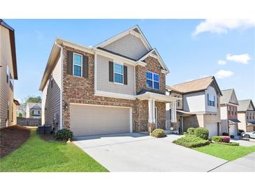 Charming two-story home featuring a two-car garage, brick accents, and a well-manicured lawn, making it a cozy suburban residence at 2463 Turnbury Glen Walk, Snellville, GA 30078