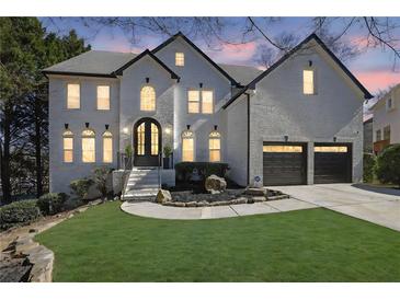 Beautiful two-story home featuring a brick facade, well-manicured lawn, and a two-car garage at 340 Willow Crescent Way, Johns Creek, GA 30022