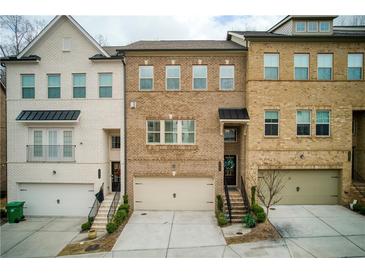 Three-story townhome with brick facade, attached garages, and landscaped entryways at 5047 Chesterfield Ln, Dunwoody, GA 30338