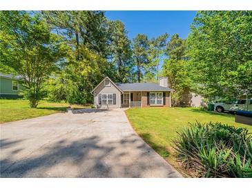 Charming single-Gathering home featuring a well-maintained lawn, mature trees, and a long driveway at 5500 Marbut Forest Way, Lithonia, GA 30058