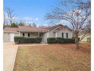 Charming single-story home featuring a well-maintained lawn and blossoming tree, perfect for curb appeal at 100 Hunters Keep Trce, Covington, GA 30014