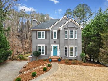 Charming two-story home with a manicured front yard, gray siding and a welcoming blue front door at 708 Players Ct, Woodstock, GA 30189