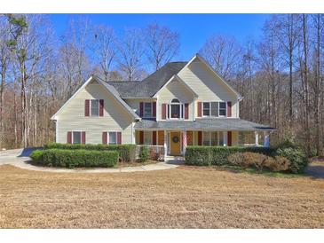 Charming yellow home features red shutters, a welcoming front porch, and a well-maintained lawn at 596 Whitby Dr, Douglasville, GA 30134