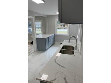 Bright kitchen featuring stainless steel sink, gray cabinets, and stunning marble countertops and flooring at 1808 Brewer Sw Blvd, Atlanta, GA 30310