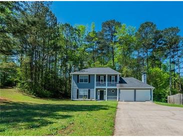 Charming two-story home features a double garage, front porch, well-manicured lawn, and beautiful landscaping at 3534 S Portsmouth Cir, Lithonia, GA 30038