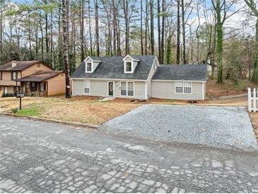 Charming single-Gathering home with gray siding, dormer windows, and a gravel driveway at 806 Longfellow Ct, Stone Mountain, GA 30088