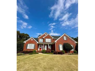 Charming brick home with manicured lawn, red front door, and classic architectural details at 3585 Shepherds Ln, Loganville, GA 30052