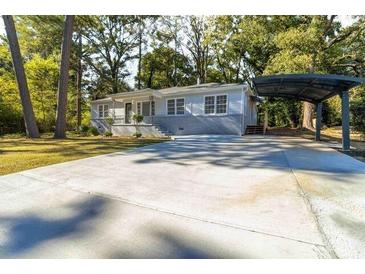 Charming single-story home with a long driveway and carport, nestled among mature trees at 1652 Pine Cir, Austell, GA 30168
