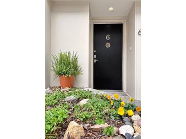 A stylish black front door with the number 6, framed by lush greenery and charming yellow flowers at 835 Glendale Ne Ter # 6, Atlanta, GA 30308