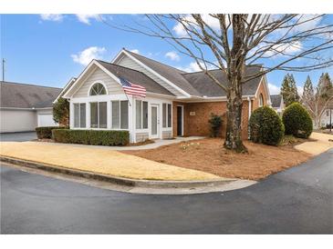 Charming single-story home with brick and siding exterior, landscaped yard and American flag at 10104 Windrush Ln, Alpharetta, GA 30009
