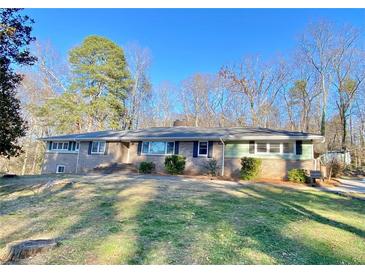 Charming brick and green home with manicured lawn and mature trees, offering a serene setting at 6787 Hembree Dr, Austell, GA 30168