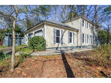 Charming two-story home featuring neutral siding, dark shutters, mature landscaping, and an attached two-car garage at 858 Huntington Nw Way, Lilburn, GA 30047