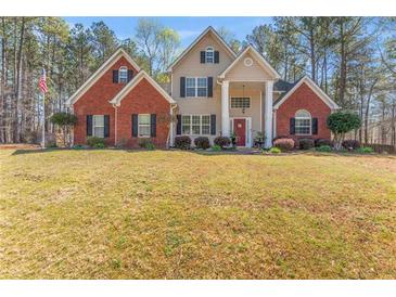 Beautiful two-story brick and tan home with manicured lawn and mature trees at 308 Helena Pl, Mcdonough, GA 30252