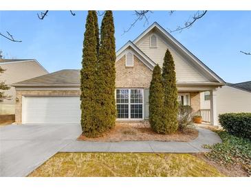 Charming brick home featuring manicured front yard with mature landscaping, and an attached two-car garage at 6690 Cold Stream Dr, Cumming, GA 30040