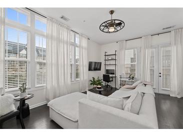 Bright living room featuring large windows with sheer curtains, dark hardwood floors, and stylish decor at 3933 Danube Ln # 221, Atlanta, GA 30339