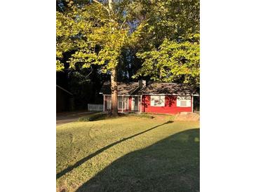 Charming one-story red home with green grass and mature trees in a peaceful setting at 650 Robert E Lee Pkwy, Jonesboro, GA 30238