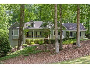 Charming, light green home with a welcoming front porch and lush, wooded surroundings on a naturally landscaped lot at 90 Lakeside Dr, Hiram, GA 30141