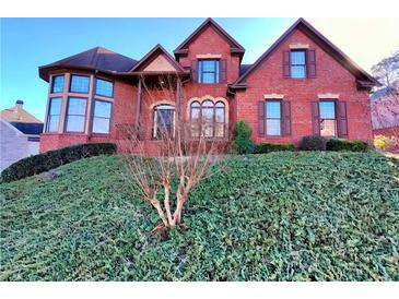 Charming red brick two-story home with manicured lawn, dark shutters, and a bay window at 11365 Donnington Dr, Duluth, GA 30097