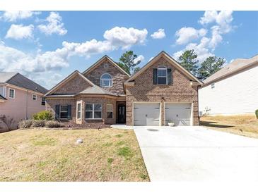 Charming two-story brick home boasts a two-car garage, mature landscaping, and a well-maintained lawn at 3777 Shady Maple Dr, Lithonia, GA 30038