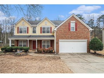 Charming two-story home with brick and siding exterior, red shutters, well-manicured landscaping, and two car garage at 750 Beckenham Walk Dr, Dacula, GA 30019