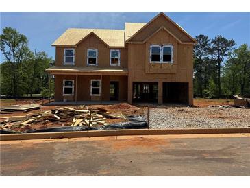 Unfinished two-story home featuring a two-car garage and a yard with construction materials at 1587 Sungrown Way, Mcdonough, GA 30253