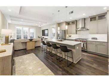 Open-concept kitchen with stainless steel appliances, island with seating, and hardwood floors flows to the living room at 58 Canton St # 302, Alpharetta, GA 30009